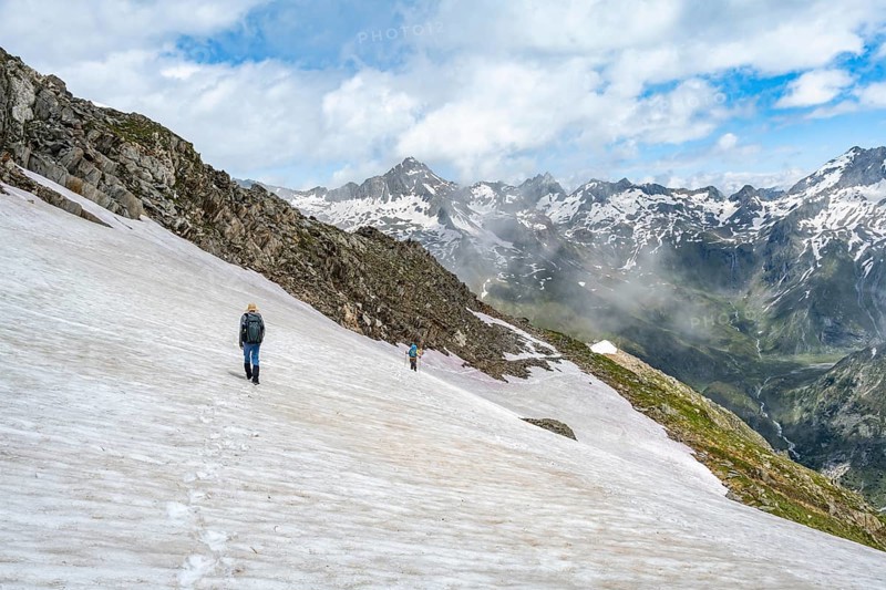 Mountaineer on a snowfield, descent from the summit of the Schönbichler Horn, view of snow-covered mountain peaks and the Zemmgrund valley, Berliner Höhenweg, Zillertal Alps, Tyrol, Austria, Europe