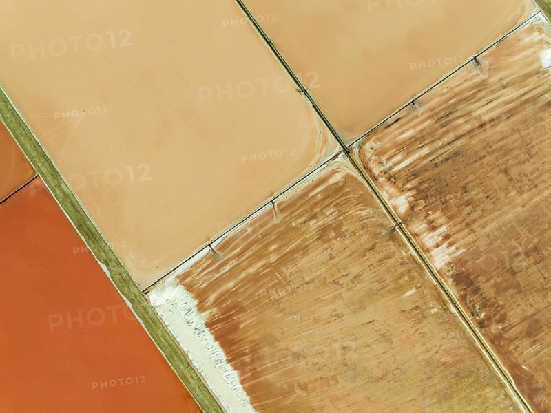 Saline ponds at the salt works next to Almadraba de Monteleva. The reddish colour depends on the level of salinity and is directly caused by the algae Dunaliella salina and brine shrimp. Aerial view. Drone shot. Nature Reserve Cabo de Gata-Nijar, Almería province, Andalusia, Spain, Europe