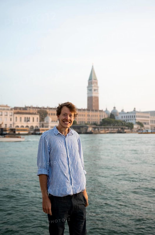 Young man in striped shirt and shorts on the banks of the Grand Canal, behind Campanile, Venice, Veneto, Italy, Europe