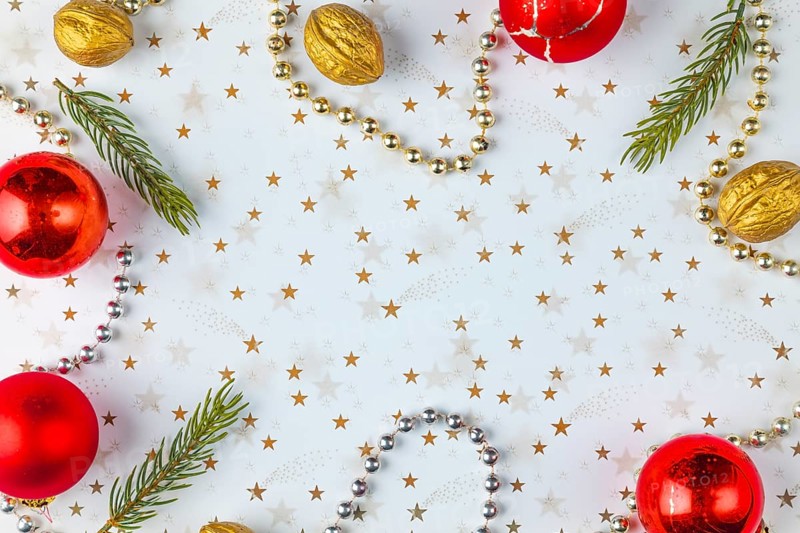 Frame made of Christmas decorations, fir branches, baubles, nuts on a white background with golden stars, copy room