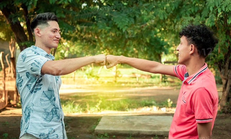 Two young men clashing their fists, image of two young men bumping their fists in a friendly way, close up of two fists bumping in a friendly way