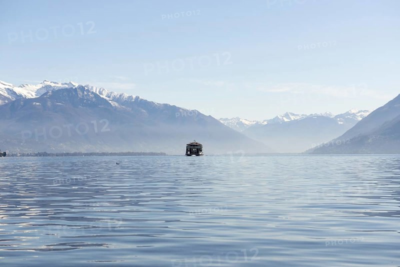 Passenger Ship on an Alpine Lake Maggiore with Snow Capped Mountain in a Sunny Day in Locarno, Ticino, Switzerland, Europe