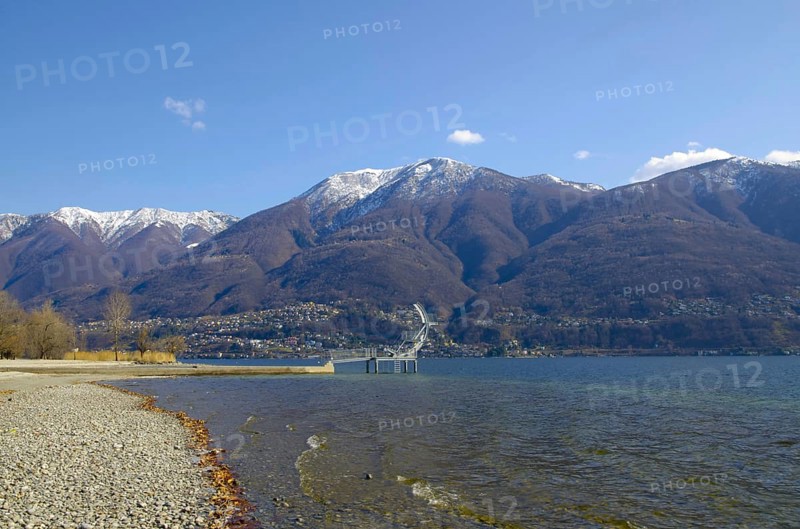 Diving Board on an Alpine Lake Maggiore with Snow Capped Mountain and Blue Sky in a Sunny Day in Ascona, Ticino, Switzerland, Europe