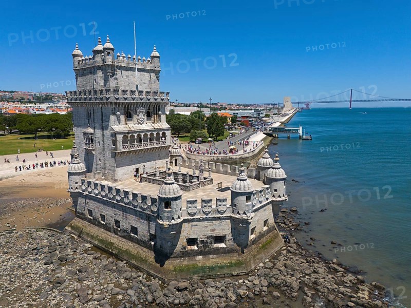 A tower on a riverbank with a bridge in the background and a clear blue sky, aerial view, Torre de Belém, World Heritage Site, Belem, Bethlehem, Lisbon, Lisboa, River Tagus, Portugal, Europe
