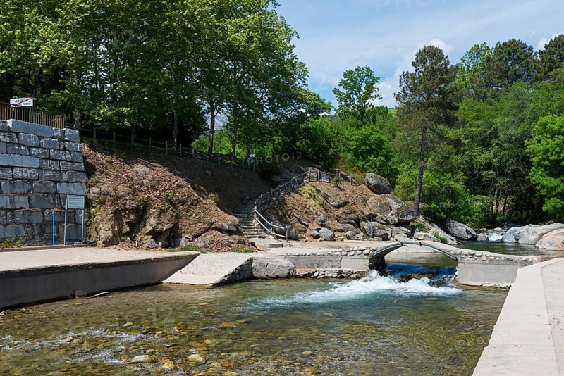 Ein ruhiger Fluss fließt durch ein Gebiet mit einer kleinen Brücke und einer Steintreppe, umgeben von Felsen und üppigem Grün, Piscinas naturales, natürliche Pools, Schwimmbad, Arenas de San Pedro, Fluss Arenal, Ávila, Avila, Kastilien-León, Kastilien-Leon, Spanien