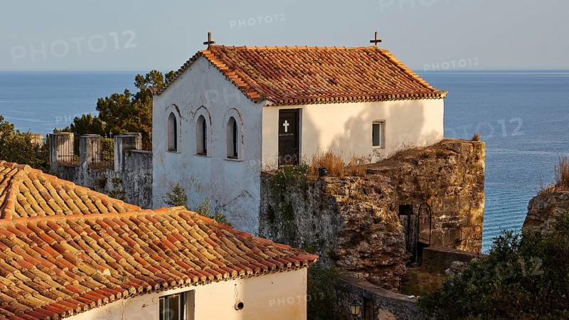 A white house with a church in the background against the sea in the evening sun, Koroni, Byzantine fortress, nunnery, Peloponnese, Greece, Europe