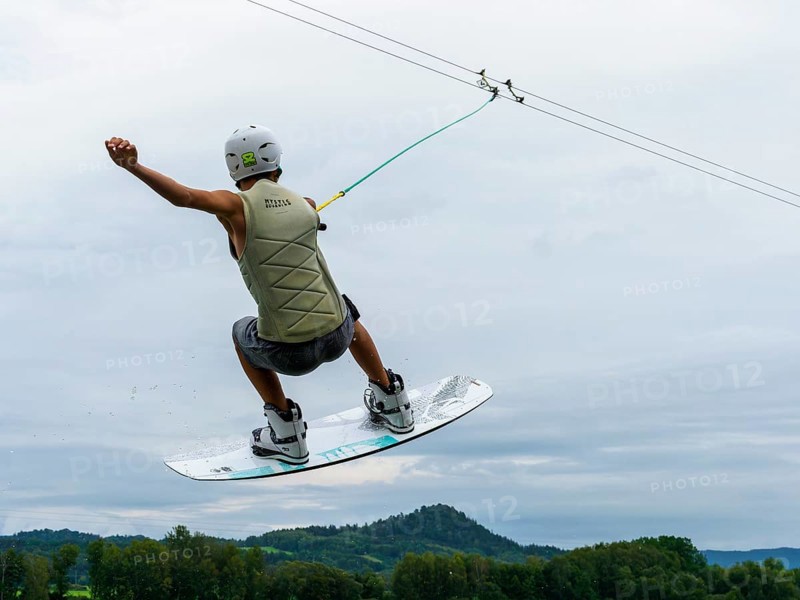 Young man jumping with wakeboard over the lake, water sports, water skiing in wakepark, Stráž pod Ralskem, Czech Republic, Europe