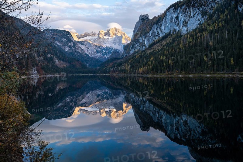The Vordere Gosausee lake in autumn with a view of the Dachstein mountain range. The Gosaukamm on the right. Clouds in the blue sky and above the mountain peak. Reflection. Golden hour. Vorderer Gosausee, Gosau, Gosau valley, Salzkammergut, Upper Austria, Austria, Europe