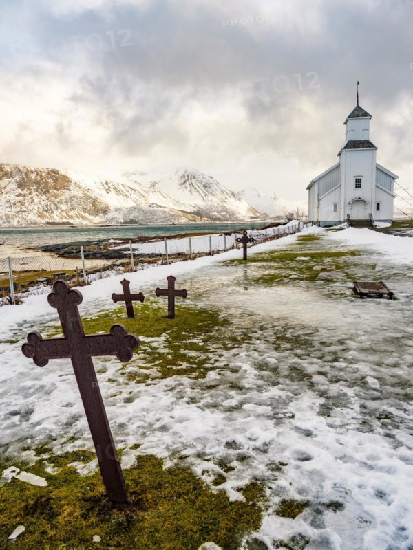 Gimsøy church with cemetery, snow-covered mountains in the background, winter, Gimsøya, Lofoten, Norway, Europe