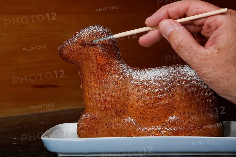 Swabian cuisine, baking, preparation of Easter lamb, baked dough, painting the eye, brush, sweet sponge, pastry for Easter, cake, typical Swabian, traditional cuisine, food photography, man's hand, studio, Germany, Europe