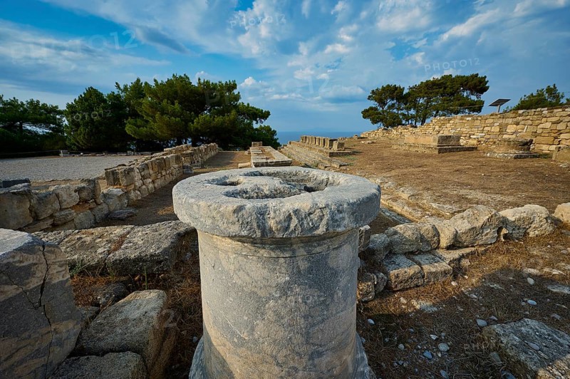 Stone column in the middle of an ancient ruins field with trees and stone structures in the background, Exedra, Kamiros, Archaeological site, Ancient city, Foundation of Doric Greeks, Rhodes, Dodecanese, Greek Islands, Greece, Europe