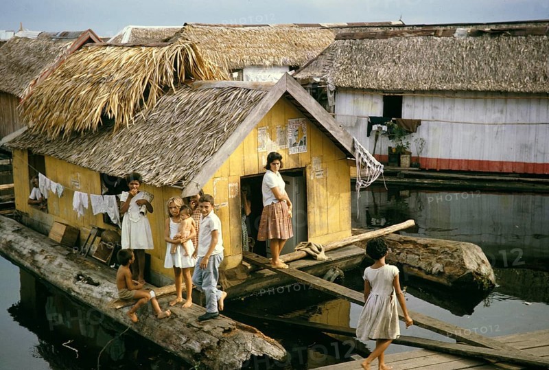 Woman and children in an informal housing area with wooden huts built on logs, known as the floating city, Manaus, Brazil 1962, which was removed as part of the slum clearance policy in the late 1960s