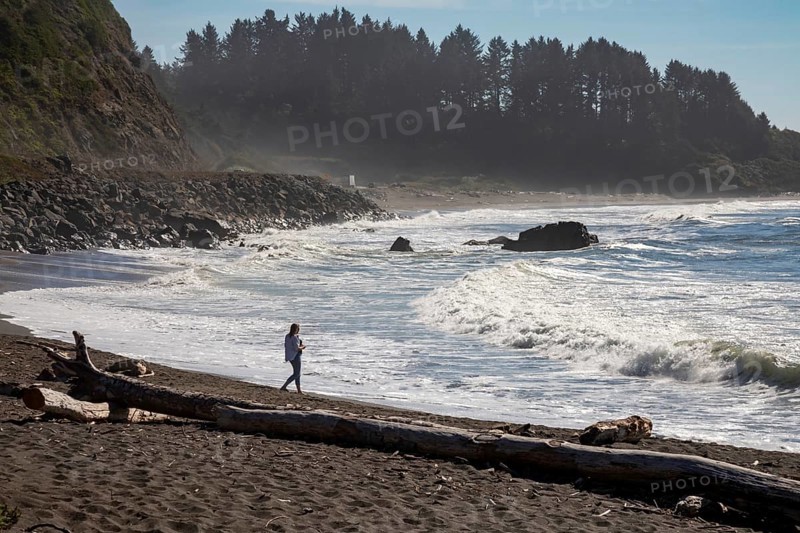 Crescent City, California - A woman walks on the beach of the Pacific Ocean in northern California