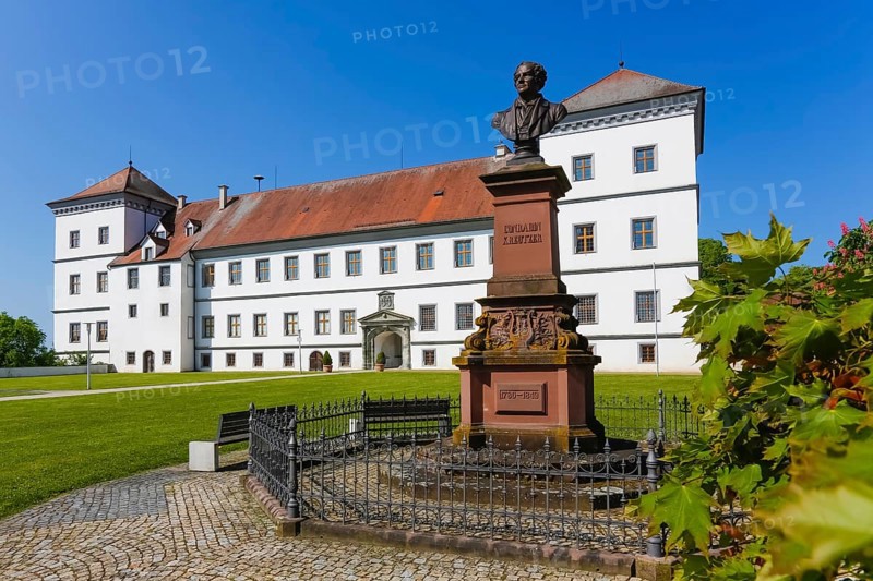 Monument in honour of Conradin Kreutzer, musician, conductor and composer, bust of Hans Baur, sculptor, sculpture, pedestal, writing, letters, public art, statue, behind Meßkirch Castle, Castle of the Counts of Zimmern, Zimmern Castle, regular four-wing castle complex, Renaissance building, architecture, historical building, park, castle garden, fence, blue sky, cloudless, Meßkirch, Sigmaringen district, Baden-Württemberg. Germany