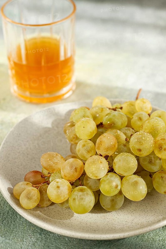 A branch of white grapes, on a gray plate, with a glass of white wine, top view, natural light, food concept, no people