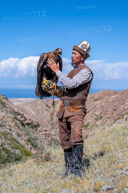 Traditional Kyrgyz eagle hunter with eagle in the mountains, near Kysyl-Suu, Kyrgyzstan, Asia