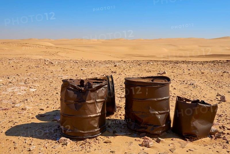 Rusty barrels stand in a vast, sandy desert landscape under a clear blue sky, Matruh, Great Sand Sea, Libyan Desert, Sahara, Egypt, North Africa, Africa