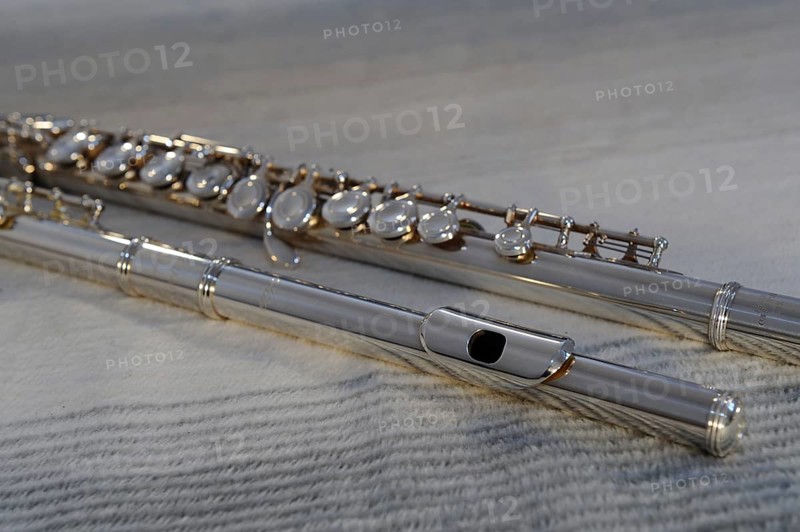 Silver transverse flute with keys on a beige background