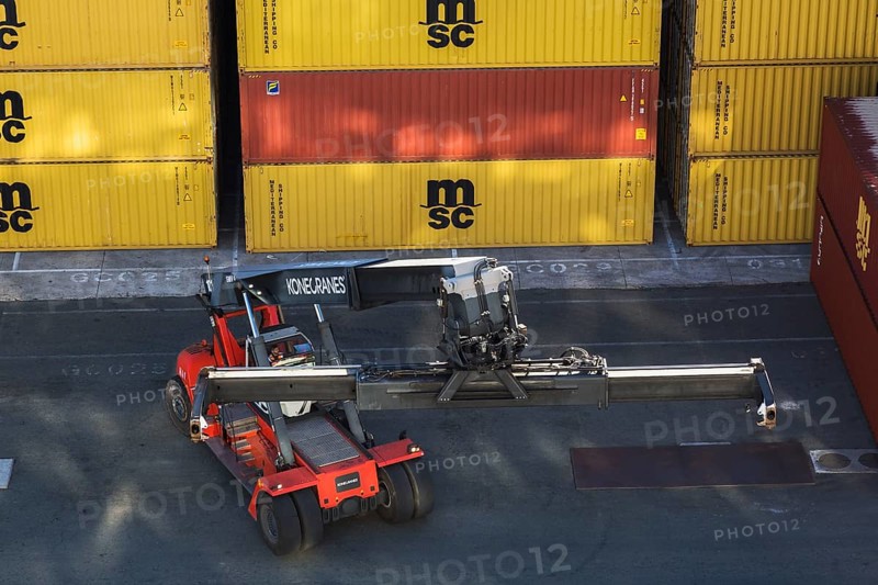 Stacked MSC, FLORENS metal box shipping containers and Kone Cranes container handler on dock in La Spezia cargo Port, Italy, Europe
