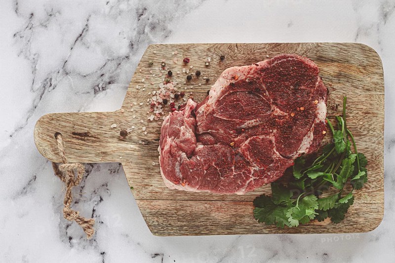 Raw pork steak, pork neck, on a chopping board, marble table, top view, with spices and coriander, no people