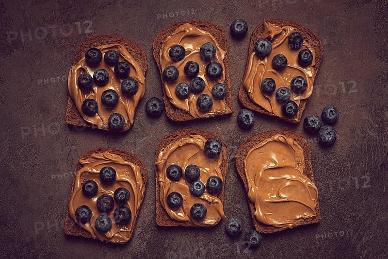 Rye bread with peanut paste and fresh blueberries, top view, no people