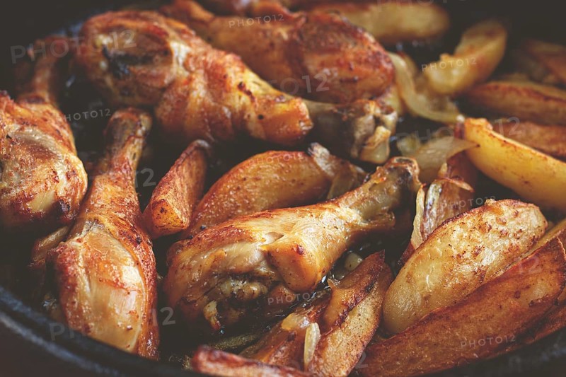 Fried chicken drumsticks with potato slices, in a clay pan, baked in the oven, with spices, homemade, no people