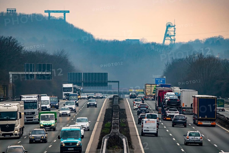 Heavy traffic on the A2 motorway at the Recklinghausen junction heading west, in the background the headframes of the former Ewald colliery, North Rhine-Westphalia, Germany, Europe