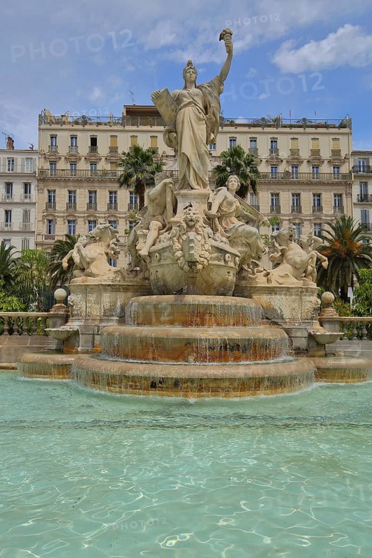 Sculptures at the Fontaine de la Fédération built in 1890, Palm trees and Grand Hotel, Statue of Liberty, Allegory, Republic, French, sculpture, arm, high, up, gesture, torch, book, plaque, carry, hold, fountain, fountain, water basin, Liberty Square, Federation, Place de la liberte, Toulon, Var, Provence, France, Europe