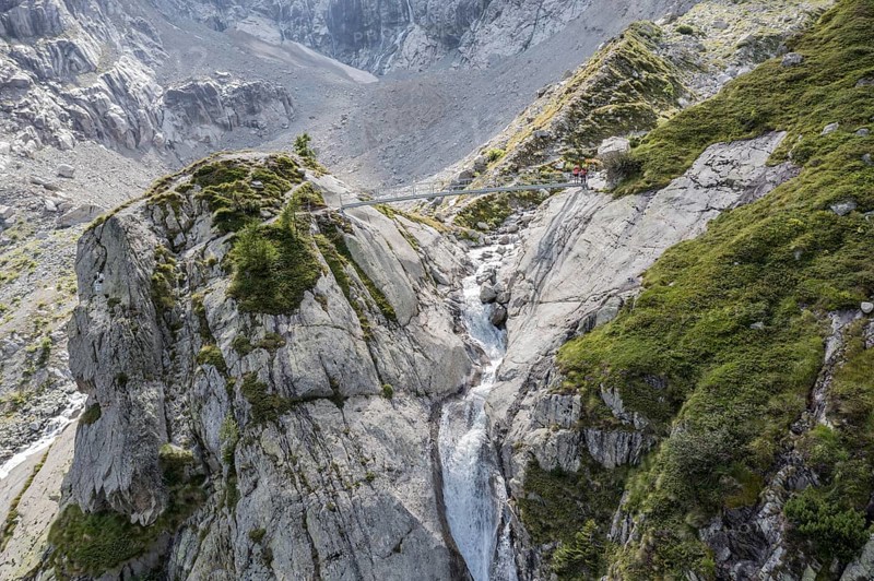 Aerial view, hikers at bridge over glacial stream, large single rock, hiking path from La Fouly to Cabane de Neuve, Valley Val Ferret, Valais, Wallis, Switzerland, Europe