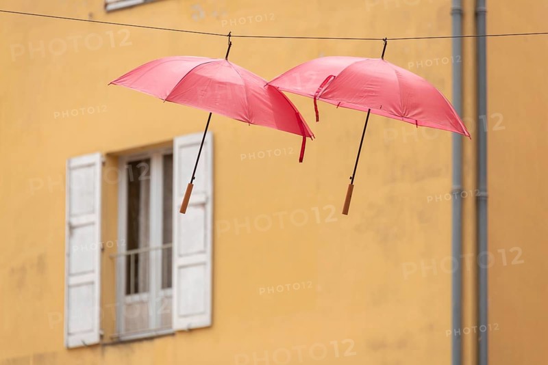Two red umbrellas, behind them a yellow house with wooden windows and shutters, Grasse, Provence Cote d'Azur, France, Europe
