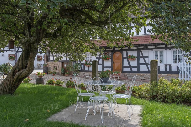 Idyllic garden with white iron furniture and half-timbered house in the background, Hunspach, Alsace, France, Europe