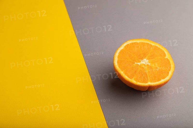 Ripe cut orange on gray and yellow pastel background. Side view, copy space. Tropical, healthy food, concept, minimalism