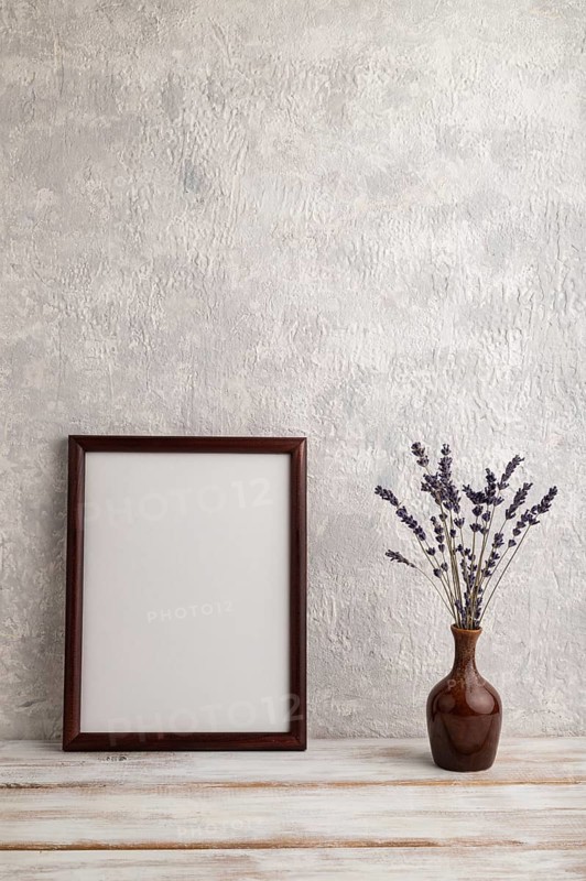 Brown wooden frame mockup with lavender in ceramic vase on gray concrete background. Blank, vertical orientation, still life, copy space