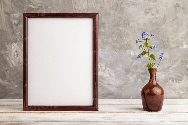 Wooden frame with blue forget-me-not flowers in ceramic vase on gray concrete background. side view, copy space, still life, mockup, template, spring, summer minimalism concept