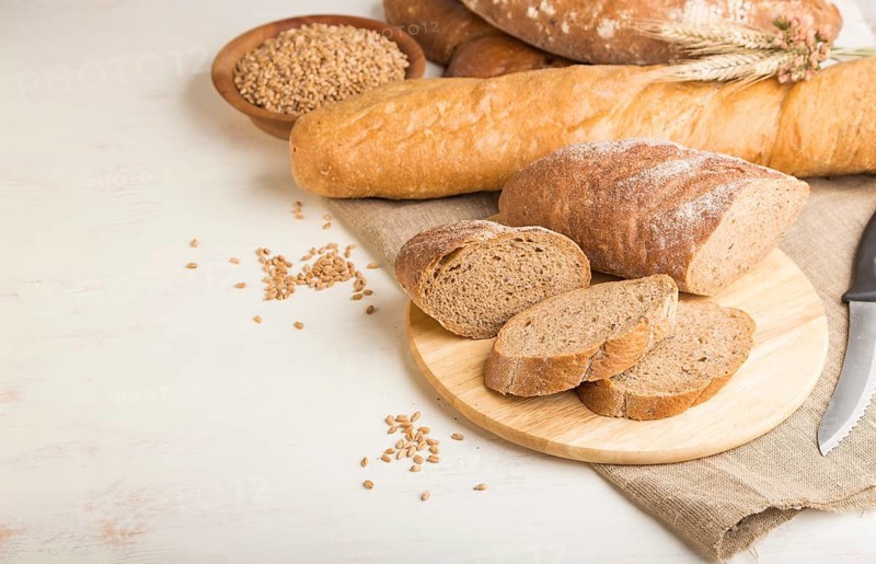 Sliced bread with different kinds of fresh baked bread on a white wooden background. side view, close up, copy space