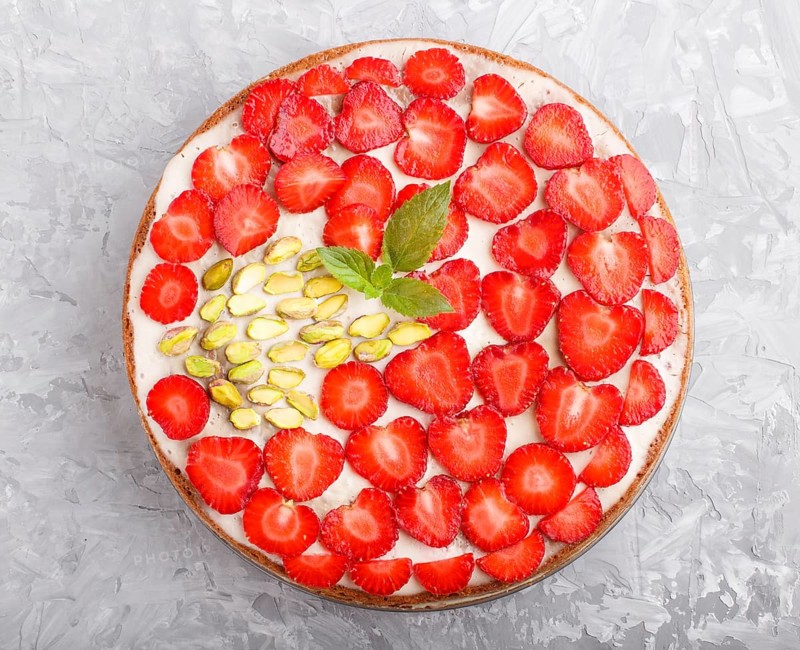 Homemade cake with yoghurt cream, strawberry and pistachio on a gray concrete background. top view. flat lay, close up