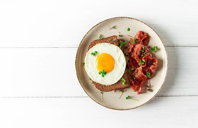 Breakfast, fried egg with bacon, micro-green, on a light background, no people, selective focus