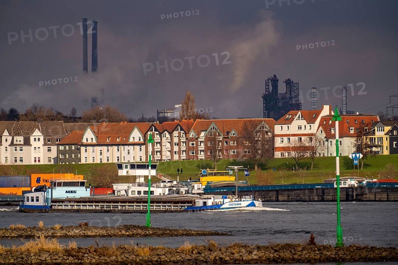 The river Rhine near Duisburg, houses on the Rhine dyke, Laar district, Thyssenkrupp Steel steelworks in Bruckhausen, cargo ship, Duisburg, North Rhine-Westphalia, Germany, Europe