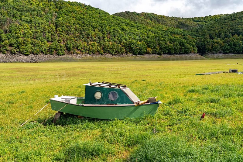 The Edersee, near Waldeck, the third largest reservoir in Germany, currently has only just under 13% of its normal level, the lake was last full in May 2022, dried up due to lack of rain, stranded fishing boat, rowing boat, the lake shore and the lake bottom is overgrown with fresh grass, Hesse, Germany, Europe