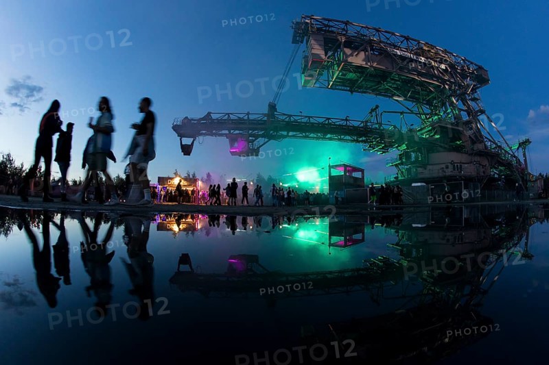 Festival visitors walk under one of the excavators at the Melt Festival in Ferropolis on 13 July 2024. After a total of 27 years, the festival will take place for the last time in 2024