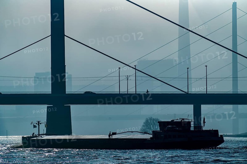 Dense fog slowly lifting, cargo ships on the Rhine near Düsseldorf, in front the Oberkassler bridge, behind it the Rheinknie bridge, North Rhine-Westphalia, Germany, Europe