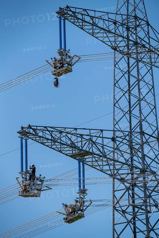 Construction of a new line route, 380 KV extra-high-voltage line between Osterath and Gohr, near Neuss, fitters in line trolleys, on the conductor cables, installing field spacers at great heights, North Rhine-Westphalia, Germany, Europe