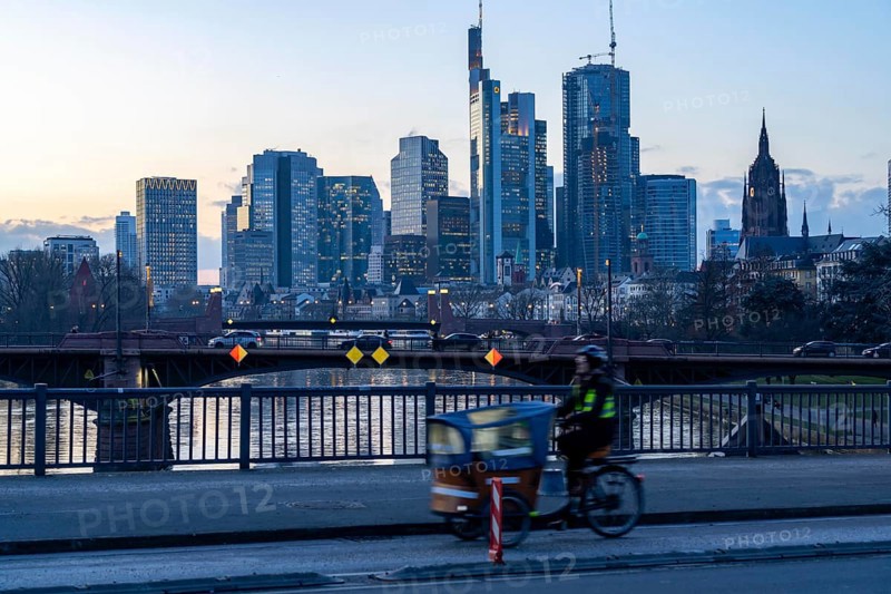 Skyline of the city centre of Frankfurt am Main, cargo bike cyclist on the rafter bridge, dusk, river Main, winter, Hesse, Germany, Europe