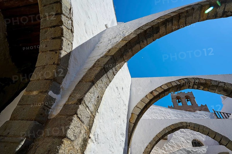 Stone arch and bell tower on a sunny day, Part of a medieval monastery with white walls, Inside the monastery, Agiou Theologou Monastery, Chora, Patmos, Dodecanese, Greek Islands, Greece, Europe