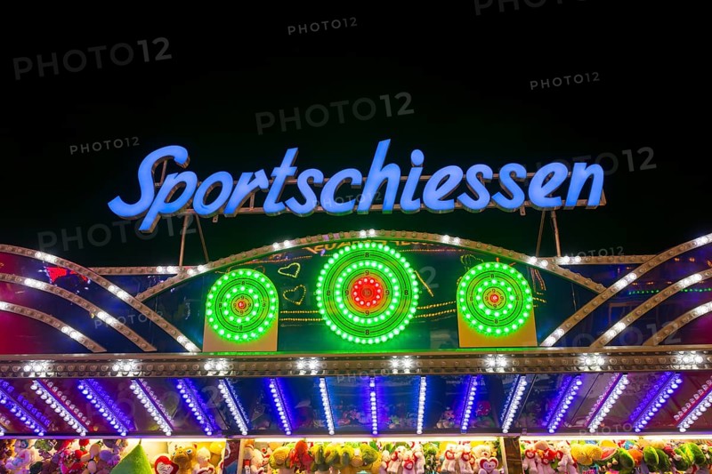 Illuminated sports shooting sign on a fairground stand with colourful lights at night, Cannstatter Wasen, folk festival, Bad Cannstatt, Stuttgart, Baden-Württemberg, Germany, Europe