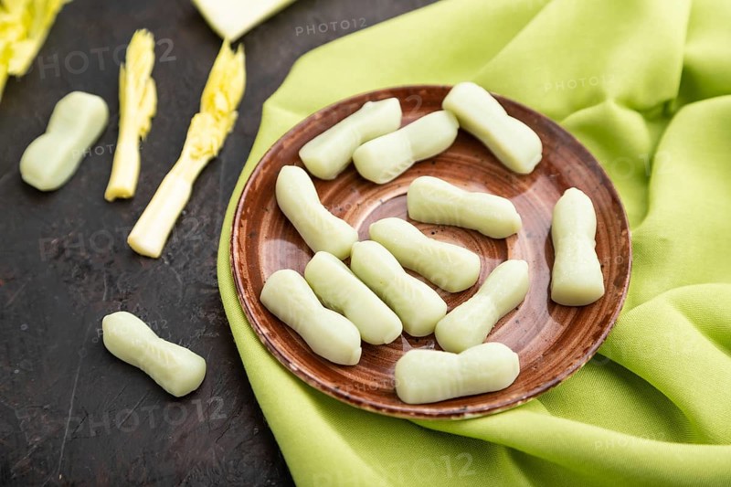 Jelly celery candies on black concrete background and green linen textile. close up, side view, selective focus