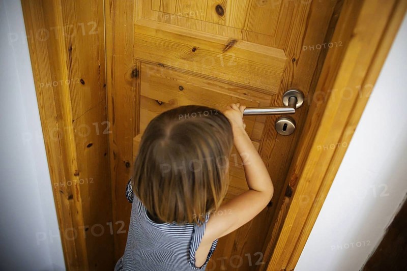 Symbolic photo: A small child tries to open a locked door. Berlin, 21.08.2024