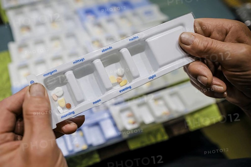 Symbolic photo on the subject of taking medication in old age. Two senior citizens sort various tablets into pill boxes at home to take for the next 16 days. Berlin, 27.07.2024