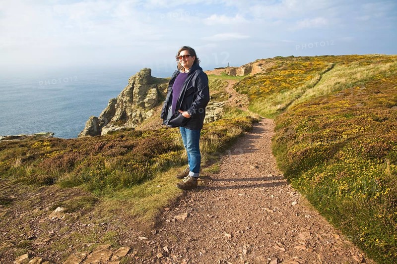 Woman wearing kagoule walking along the South West coast path at St Agnes head, Cornwall, England, United Kingdom, Europe