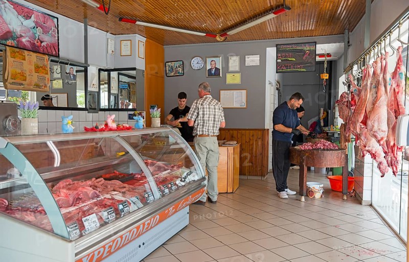 Customers and butchers in a butcher's shop full of meat products and a busy atmosphere, Gastouni, Elis, Peloponnese, Greece, Europe
